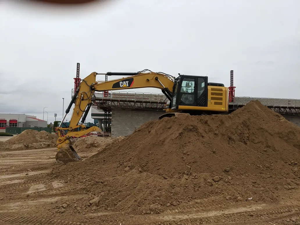 A Cat excavator perched on a working dirt pile at a commercial site, ready to break ground and clear material